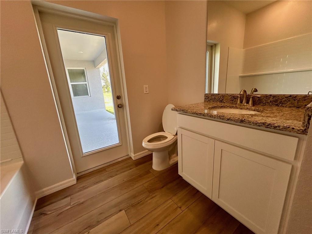 Image 4: Bathroom featuring wood finished floors, toilet, vanity, and baseboards