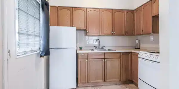Image 4: Kitchen with white appliances, tasteful backsplash, light countertops, and brown cabinets