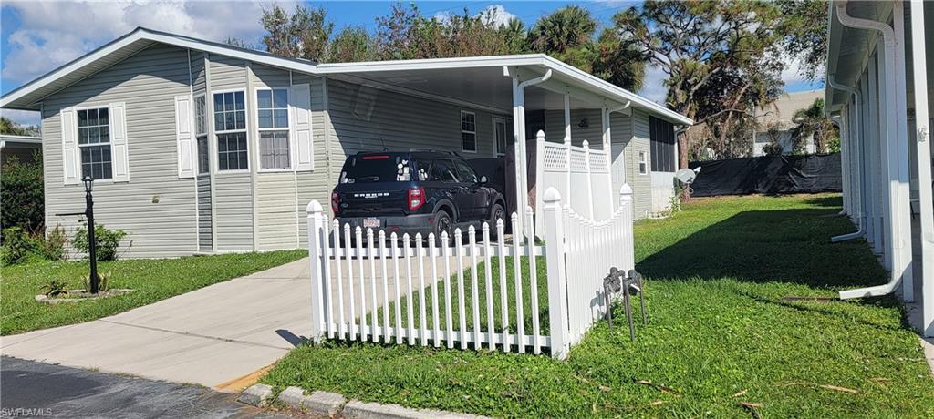 Image 2: View of home's exterior featuring a carport and a lawn