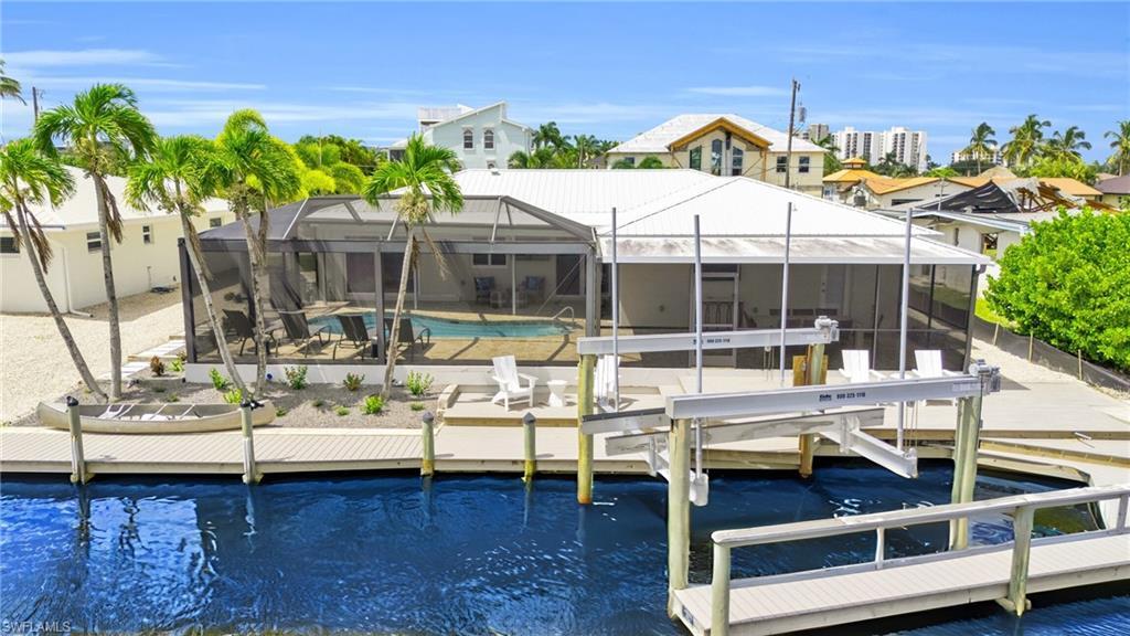 Image 1: View of the rear of the home featuring a Captains Walk Boat Dock, with a 20,000 pound Boat Lift!  VIRTUALLY ENHANCED