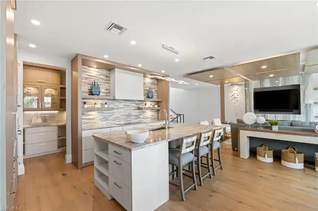 Image 1: Bar with open shelves, modern cabinets, light stone countertops, white cabinets, and pendant lighting
