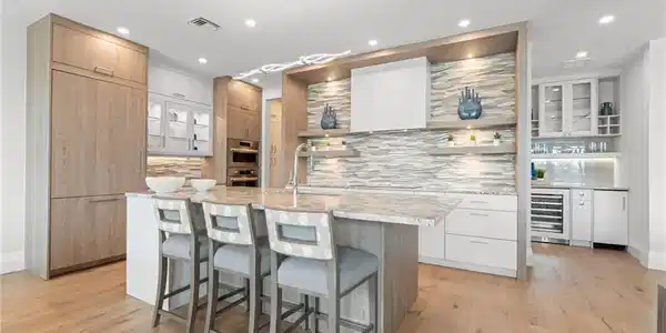Image 2: Kitchen featuring modern cabinets, open shelves, backsplash, light stone countertops, and glass insert cabinets