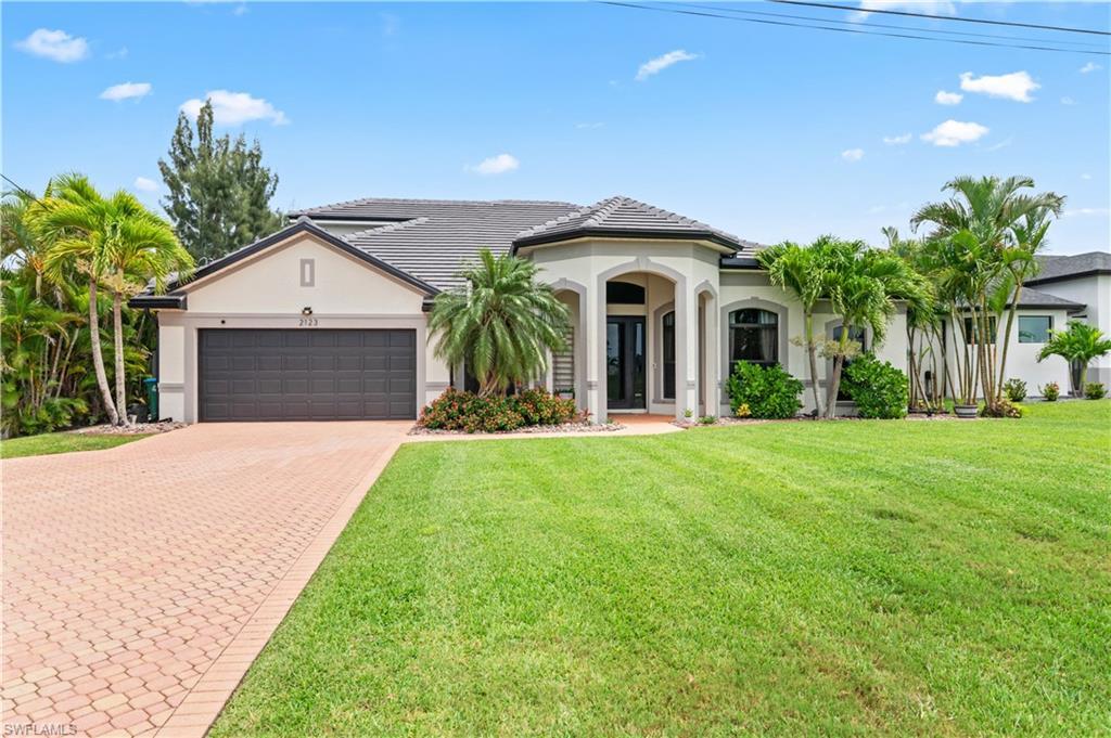 Image 1: Mediterranean / spanish-style home featuring stucco siding, decorative driveway, a front yard, and a garage