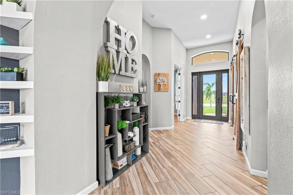 Image 4: Entryway with a barn door, a textured wall, wood finish floors, and arched walkways