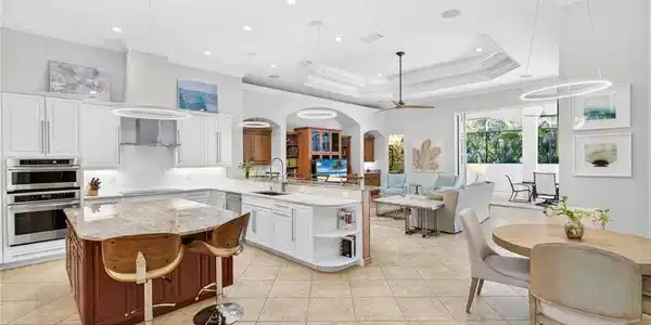 Image 3: Kitchen with light stone counters, hanging light fixtures, a peninsula, two tone color scheme, and ornamental molding