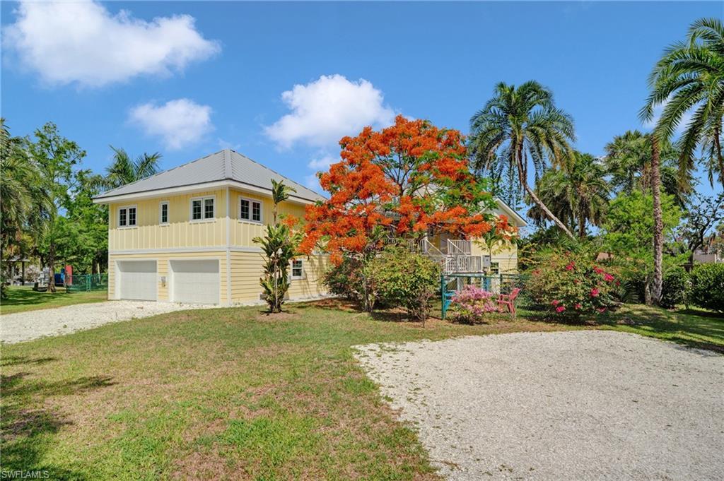 Image 3: View of back of house featuring a front lawn, driveway, and an attached garage - Virtually Edited Image
