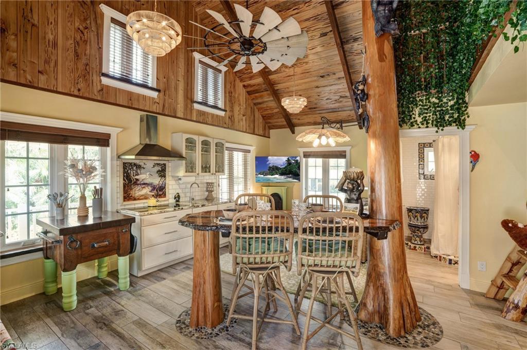 Image 4: Dining area featuring light wood-style flooring, plenty of natural light, wooden ceiling, ceiling fan, and high vaulted ceiling - Virtually Edited Image