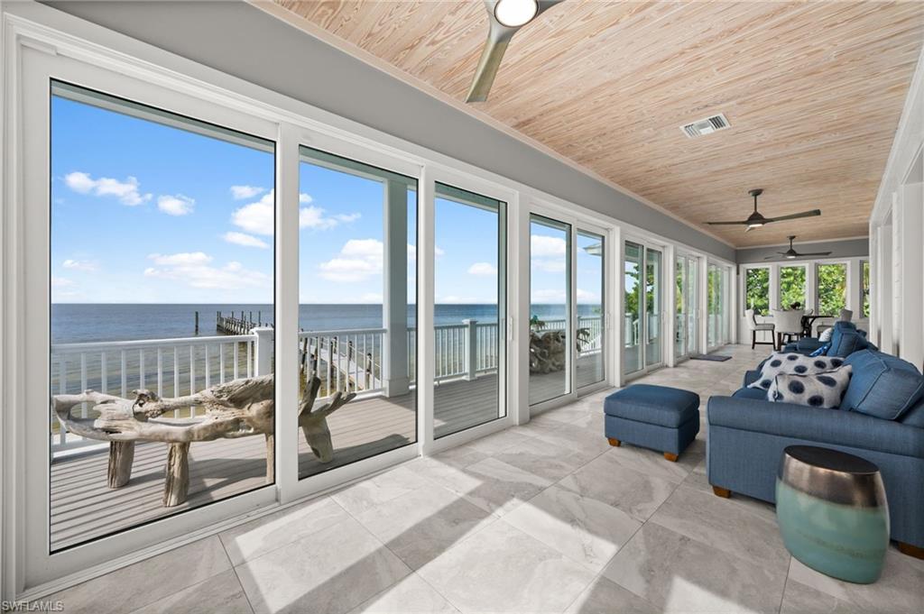 Image 2: Sunroom with a view of second floor deck, dock and water. 3 ceiling fans and wooden recessed ceiling.