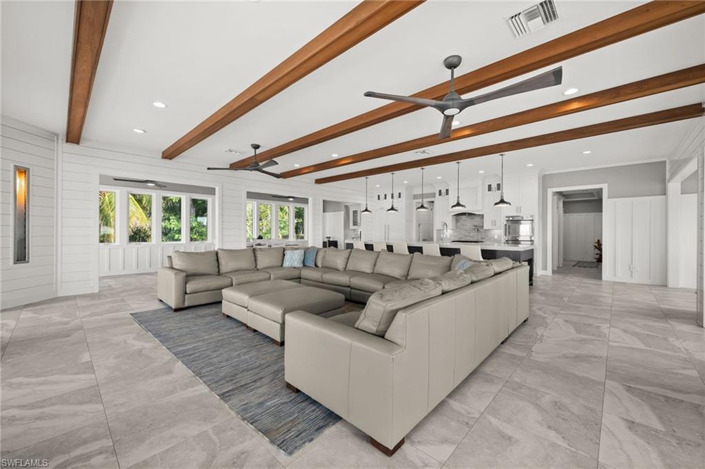 Image 3: Living room with ceiling fan, beamed ceiling, light marble finish tile floors, shiplap walls and recessed lighting