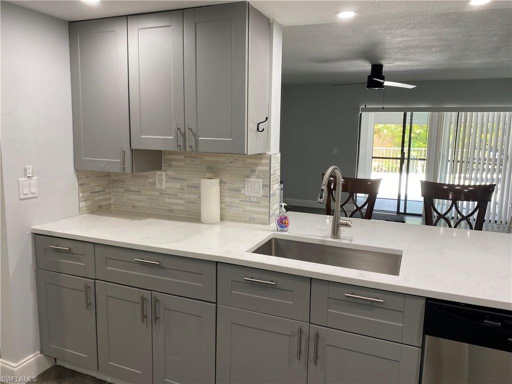 Image 3: Kitchen featuring gray cabinets, light stone counters, backsplash, recessed lighting, and a textured ceiling