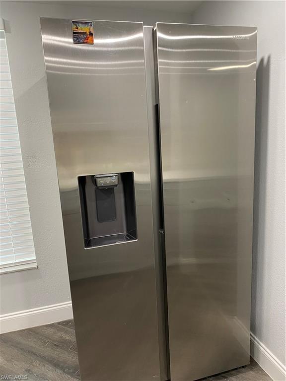 Image 4: Kitchen view of a textured wall, stainless steel refrigerator with ice dispenser, and dark wood finished floors