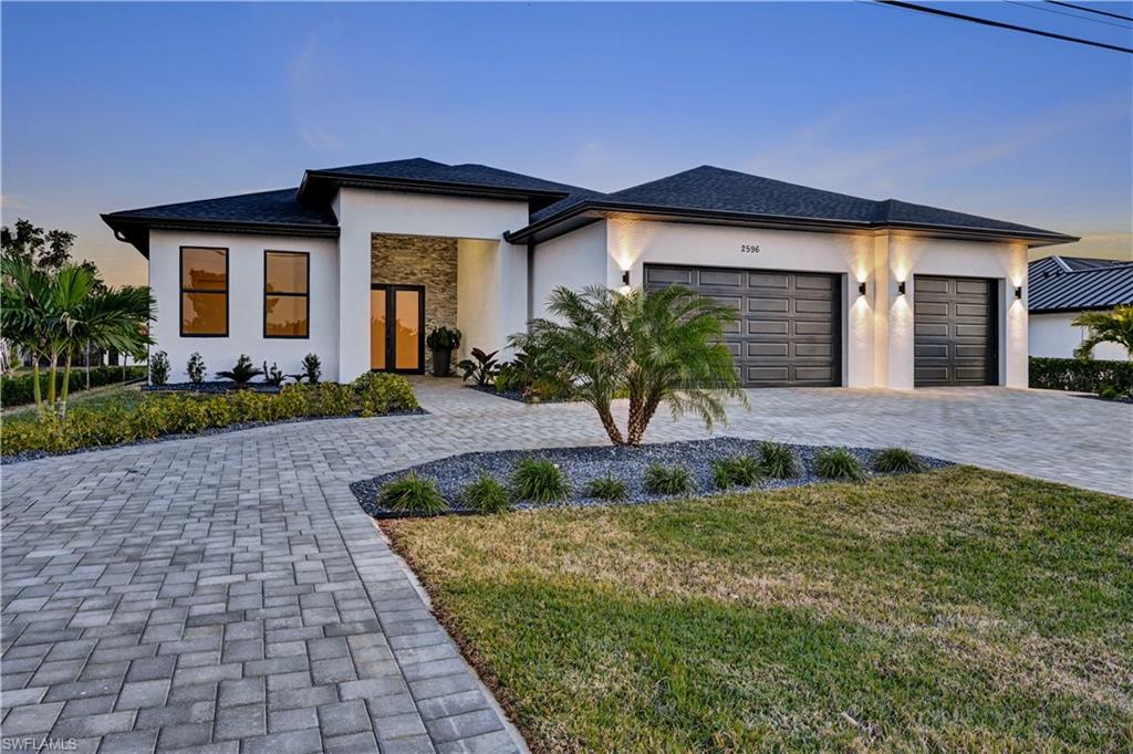 Image 3: Prairie-style home with stucco siding, decorative driveway, a front yard, and an attached garage