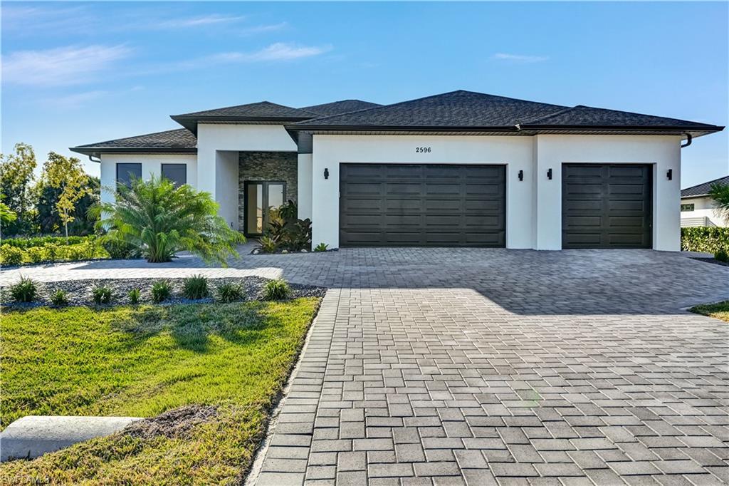 Image 4: Prairie-style home with stucco siding, decorative driveway, an attached garage, and a front lawn