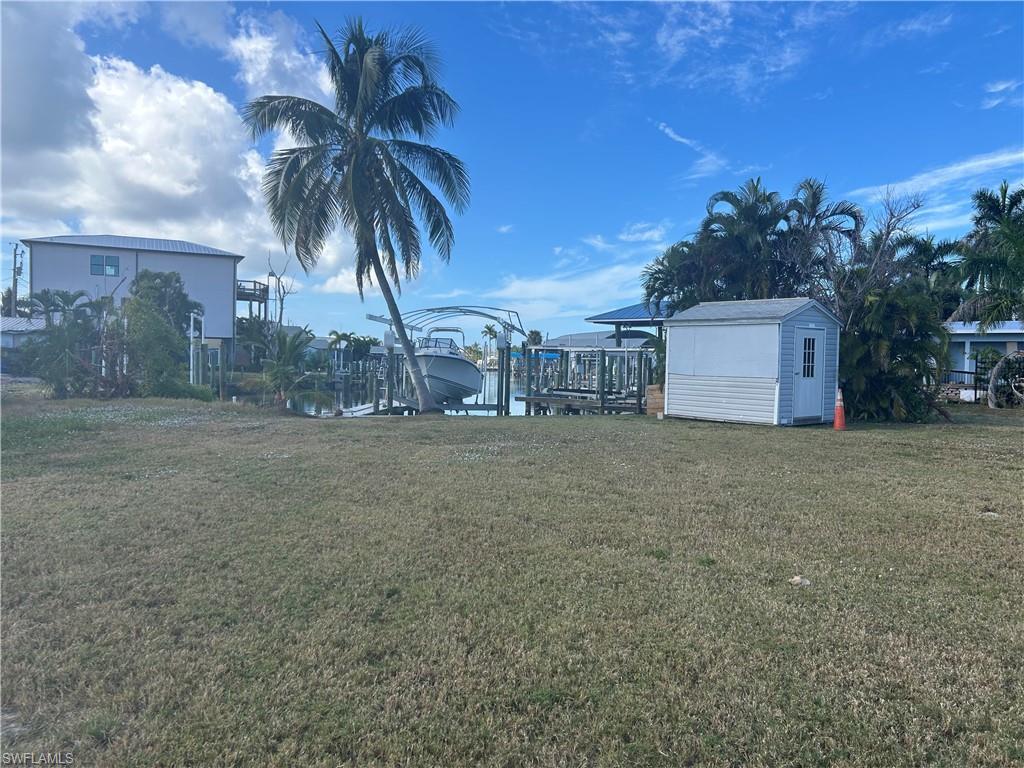 Image 2: View of grassy yard featuring boat lift, a boat dock, and a storage unit