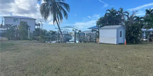 Image 2: View of grassy yard featuring boat lift, a boat dock, and a storage unit