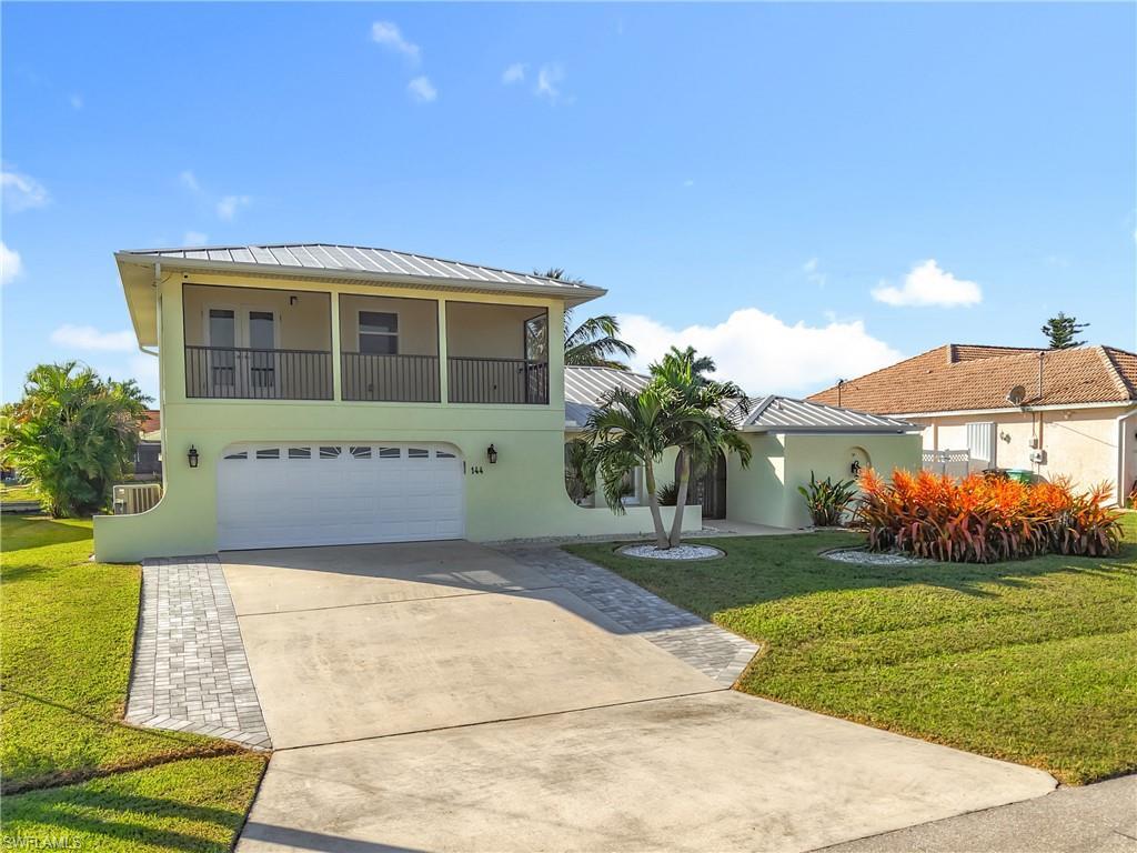Image 2: View of front facade with stucco siding, a front lawn, concrete driveway, and an attached garage
