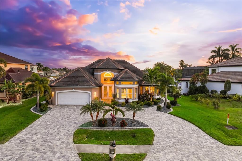 Image 1: View of front of house featuring a lawn, decorative driveway, an attached garage, and stucco siding