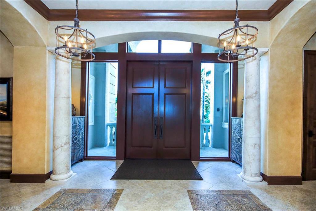 Image 4: Foyer with a chandelier, ornate columns, arched walkways, and a textured wall