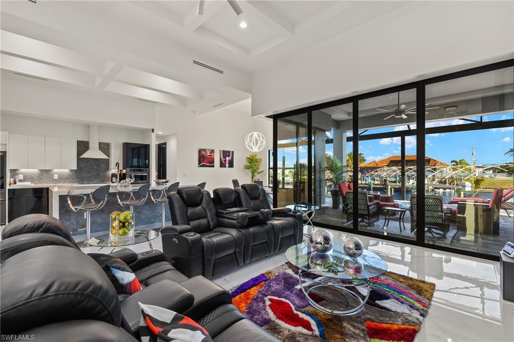 Image 3: Living room featuring a ceiling fan, coffered ceiling, beam ceiling, and a high ceiling