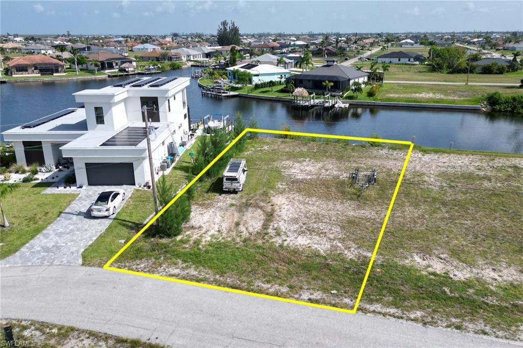 Image 1: Aerial view of residential area featuring property parcel outlined and a nearby body of water