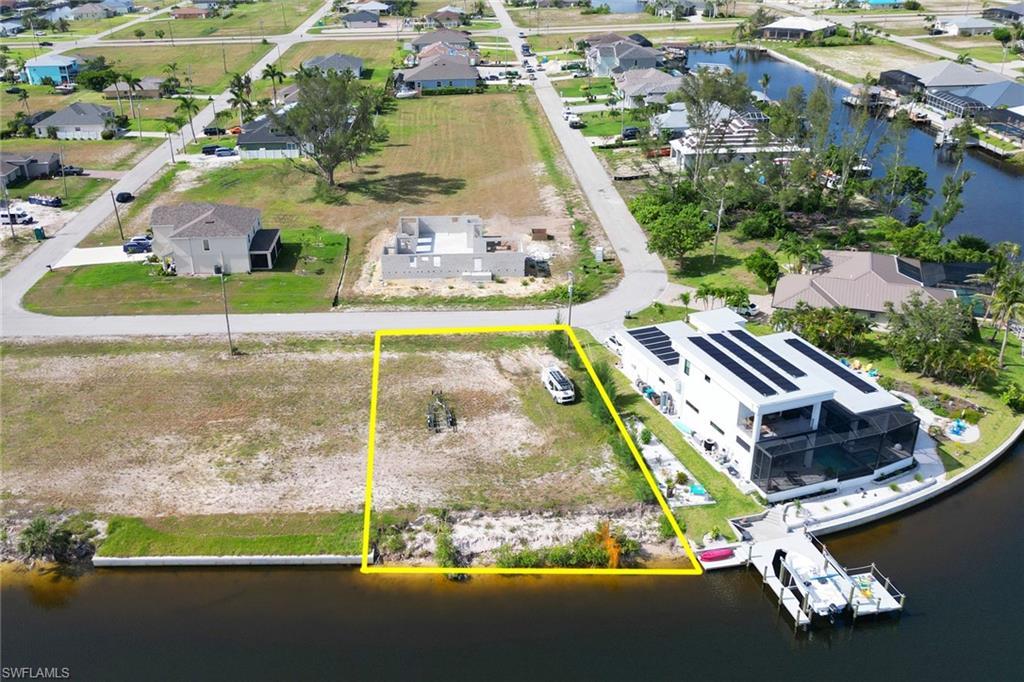 Image 4: Aerial perspective of suburban area with property parcel outlined and a large body of water