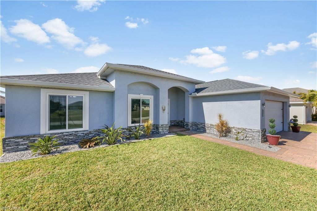 Image 2: View of front of house featuring stone siding, a garage, stucco siding, and a front yard