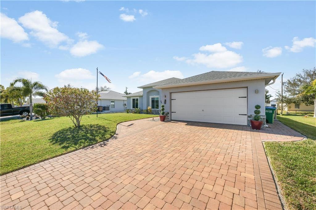 Image 3: Ranch-style home with a front lawn, decorative driveway, stucco siding, and a garage