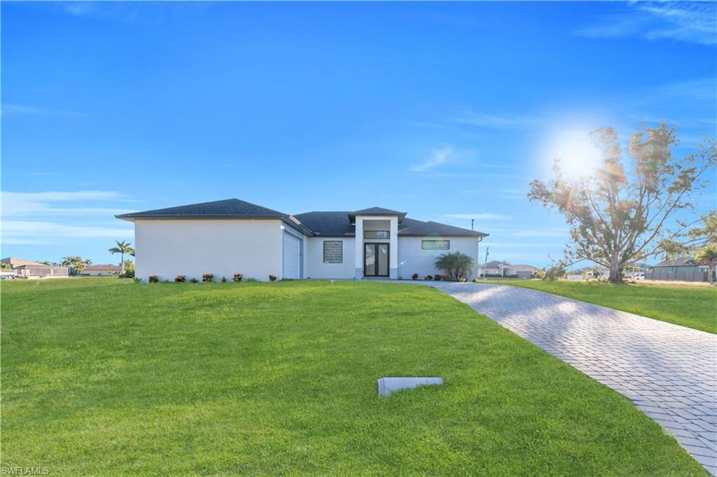 Image 1: View of front of home with a front yard, decorative driveway, and stucco siding