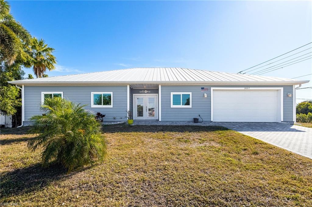 Image 1: Ranch-style house with a front yard, driveway, an attached garage, and french doors