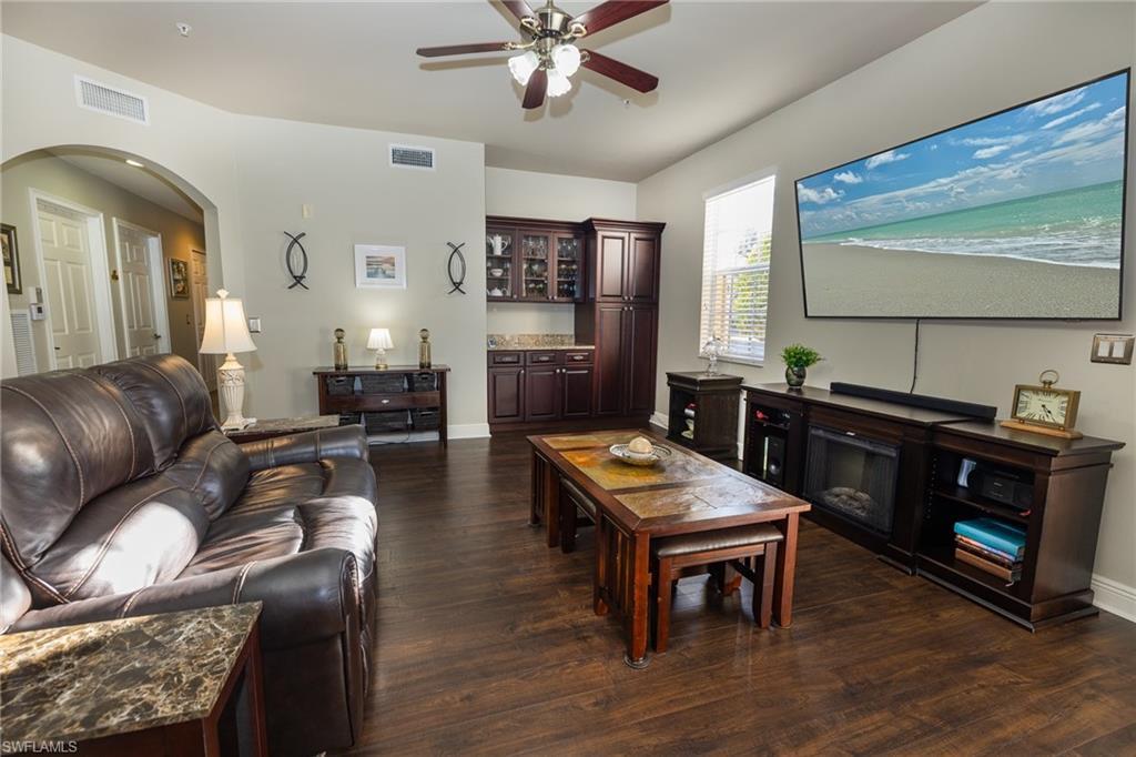 Image 2: Living area with dark wood-type flooring, ceiling fan, and arched walkways