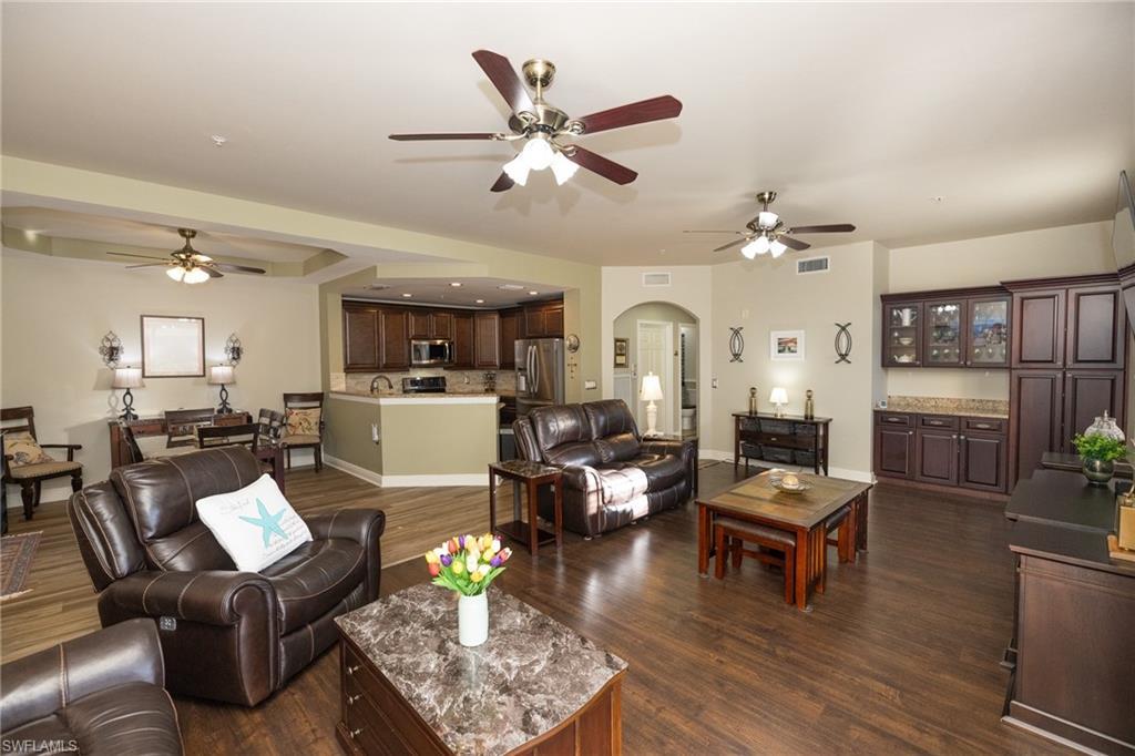 Image 4: Living area with a ceiling fan, arched walkways, dark wood-style floors, and recessed lighting