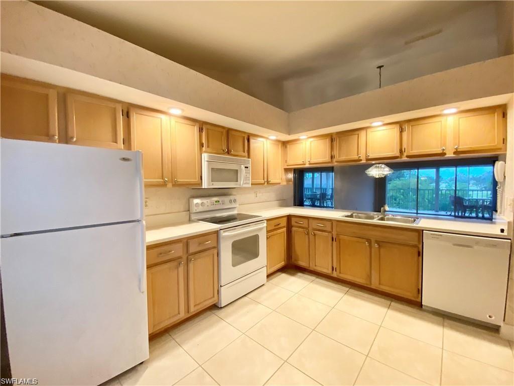 Image 3: Kitchen featuring white appliances, light countertops, light tile patterned floors, and light wood finish cabinetry