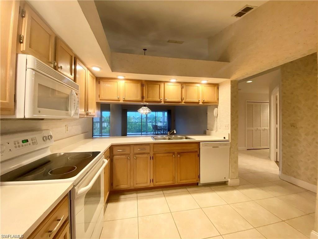 Image 4: Kitchen with white appliances, light countertops, recessed lighting, light tile patterned floors, and wallpapered walls