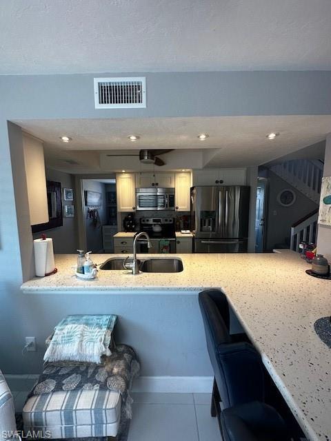 Image 3: Kitchen with fridge, a peninsula, stove, stainless steel microwave, and a textured ceiling