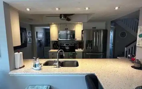 Image 3: Kitchen with fridge, a peninsula, stove, stainless steel microwave, and a textured ceiling