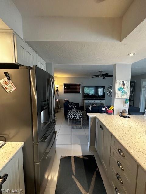Image 4: Kitchen featuring stainless steel fridge, light stone countertops, open floor plan, and light tile patterned flooring