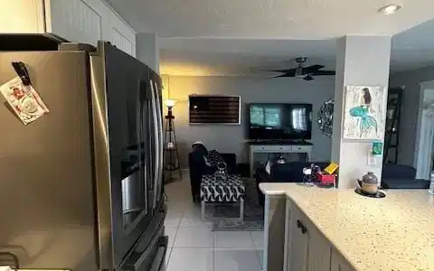 Image 4: Kitchen featuring stainless steel fridge, light stone countertops, open floor plan, and light tile patterned flooring