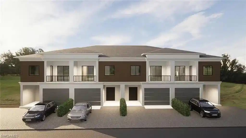 Image 1: Rear view of property with a balcony, an attached garage, and driveway