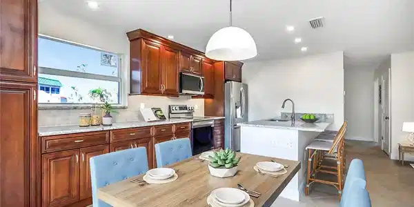 Image 3: Kitchen featuring light tile patterned floors, stainless steel appliances, tasteful backsplash, hanging light fixtures, and a breakfast bar