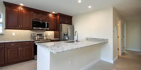 Image 4: Kitchen with appliances with stainless steel finishes, sink, kitchen peninsula, light stone counters, and light tile patterned floors