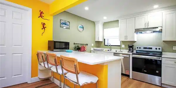 Image 3: Kitchen with white cabinets, a breakfast bar, appliances with stainless steel finishes,