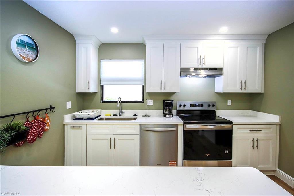 Image 4: Kitchen with white cabinets, stainless steel appliances, recessed lighting, under cabinet range hood, and a sink