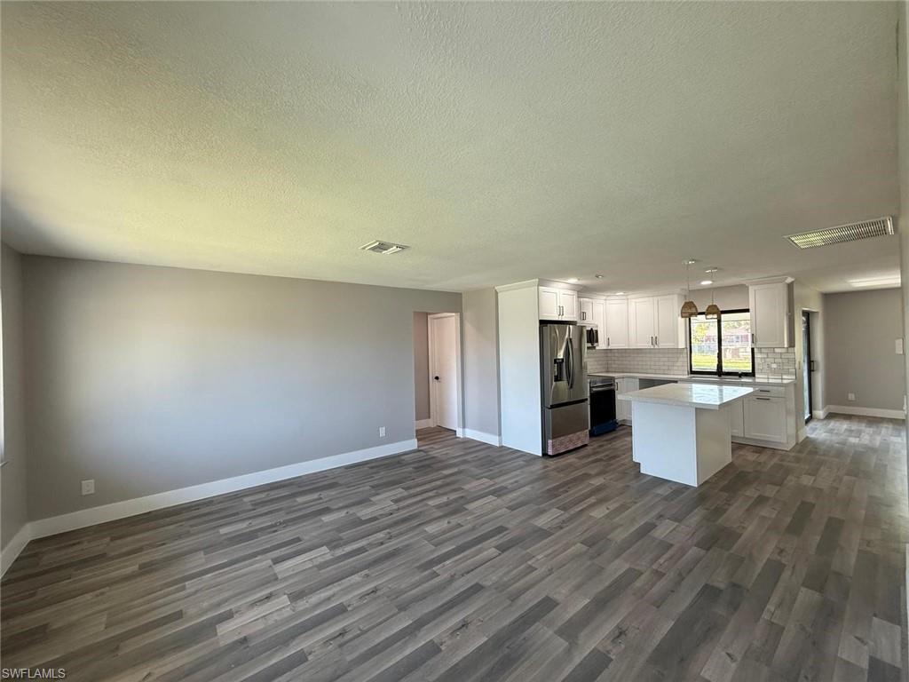 Image 4: Kitchen featuring stainless steel refrigerator with ice dispenser, dark wood-type flooring, backsplash, open floor plan, and baseboards