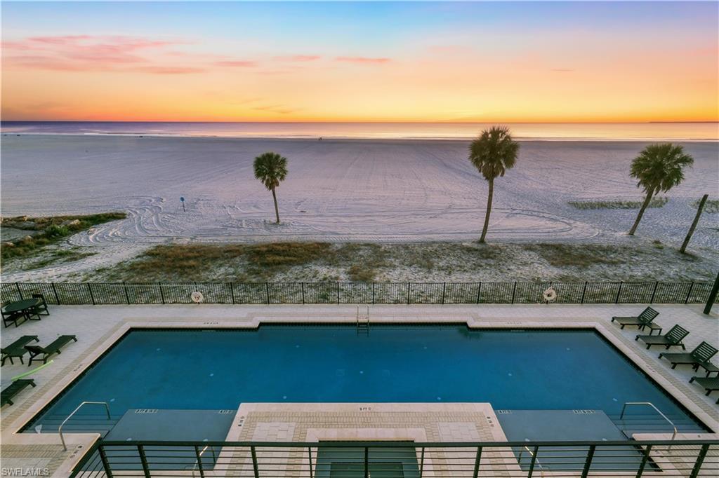 Image 1: Pool at dusk with a patio area, a water view, and a community pool