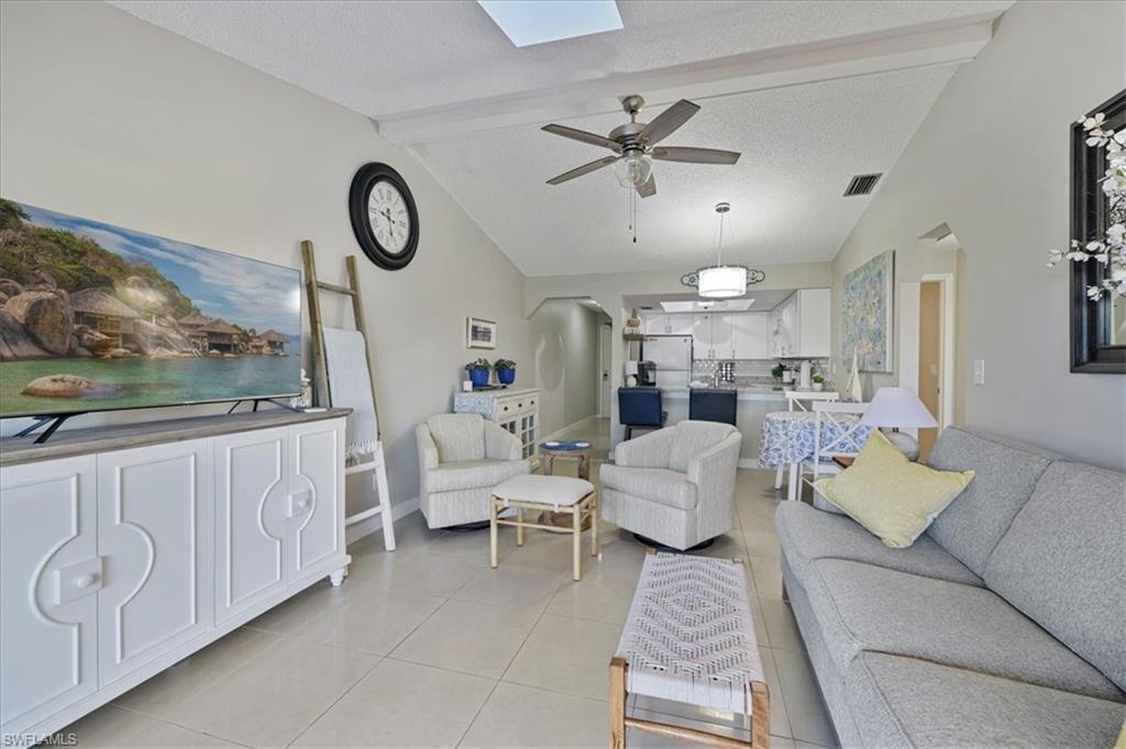 Image 2: Living room with light tile patterned floors, a textured ceiling, a skylight, arched walkways, and a ceiling fan