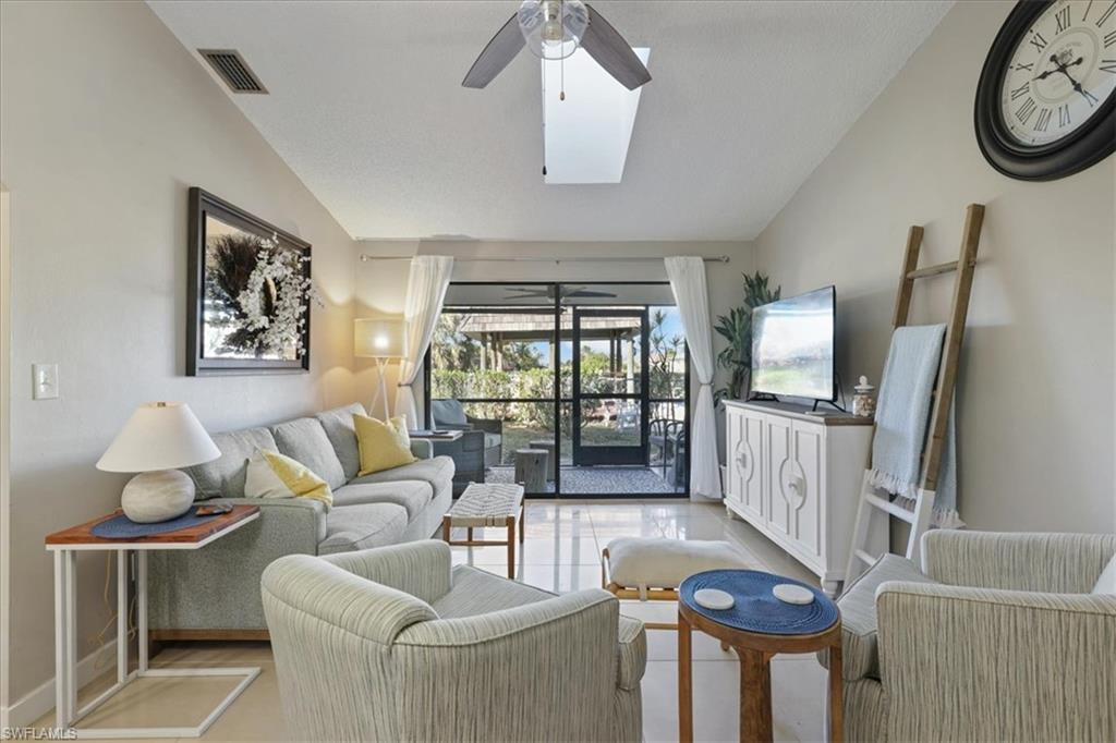 Image 3: Living room featuring vaulted ceiling, a skylight, tile patterned floors, and ceiling fan