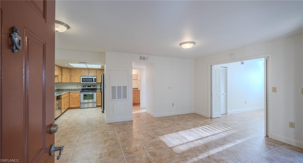 Image 4: Kitchen with stainless steel appliances, light tile patterned floors, and light countertops
