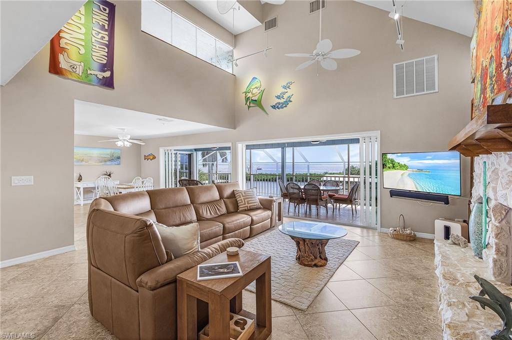 Image 4: Living room featuring ceiling fan, high vaulted ceiling, light tile patterned floors, and a sunroom