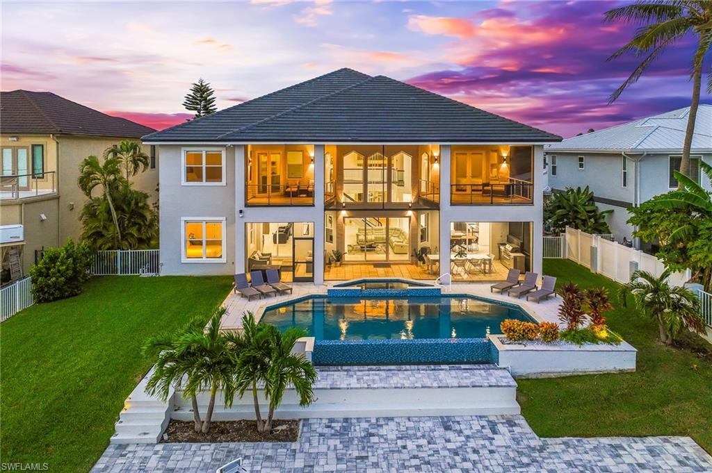 Image 1: Rear view of house featuring a balcony, a fenced backyard, a patio, stucco siding, and a pool with connected hot tub