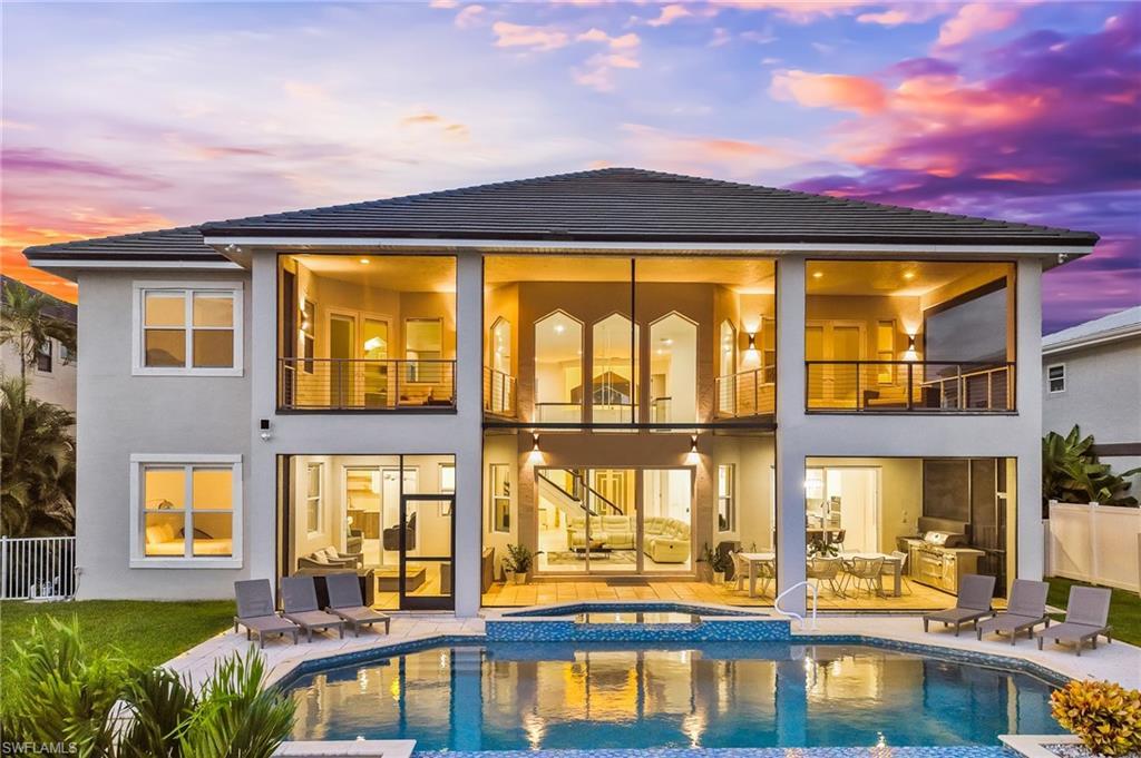 Image 3: Back of house with a balcony, a patio area, stucco siding, and a pool with connected hot tub